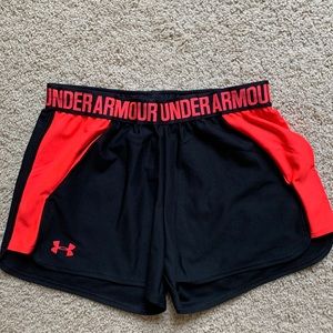 Under Armour black shorts with reddish orange accent side panels, pockets.